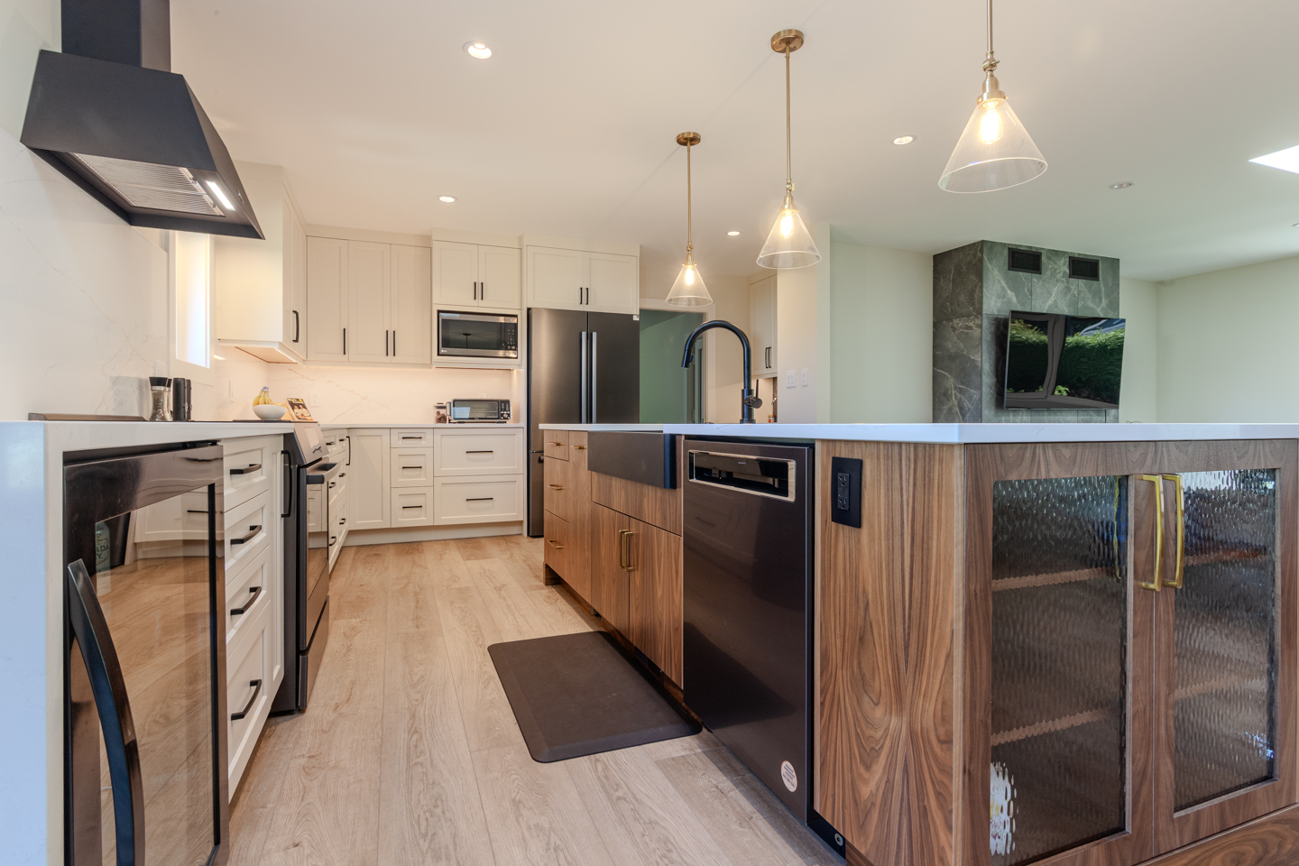 Wood kitchen island with drawers, a built-in dishwasher, sink and glass-front storage cabinets.